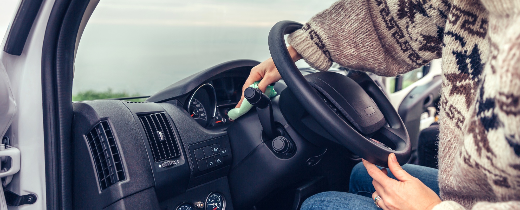 Young woman cleaning dust of the car dashboard