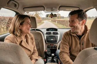 Groupe de covoitureurs adultes souriant à bord d'une voiture traversant une route de campagne française en automne