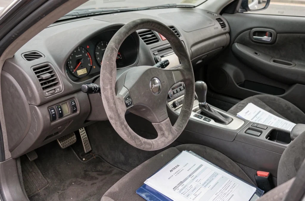 Intérieur cockpit Nissan Skyline GTR R34 avec documents d'assurance et certificat d'immatriculation japonais sur le siège passager